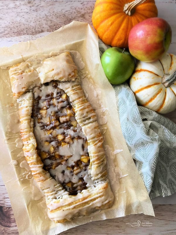 apple pumpkin strudel with icing on parchment paper