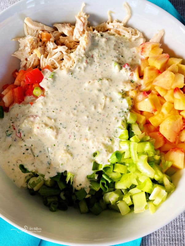 chopped ingredients and dressing in bowl with chicken