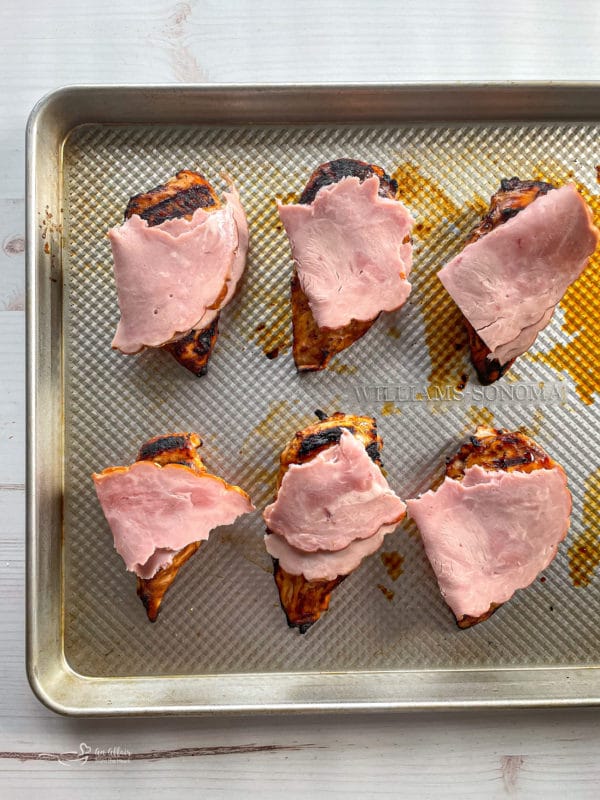 ham on top of chicken on baking sheet