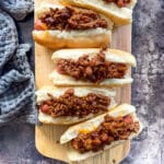 Hot dogs with chili on them on a wood board