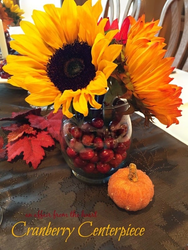 Cranberry centerpiece with large sunflowers on a festive fall table cloth