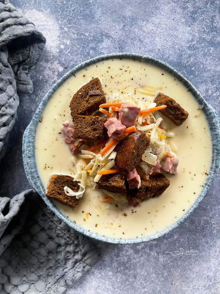 Cream of Reuben Soup in a grey pottery bowl with rye croutons