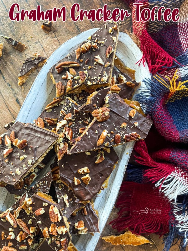 graham cracker toffee brittle on white oval plate with pecans and melted chocolate 