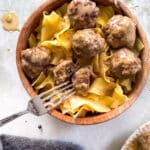 Swedish meatballs and egg noodles in a wooden bowl, up close