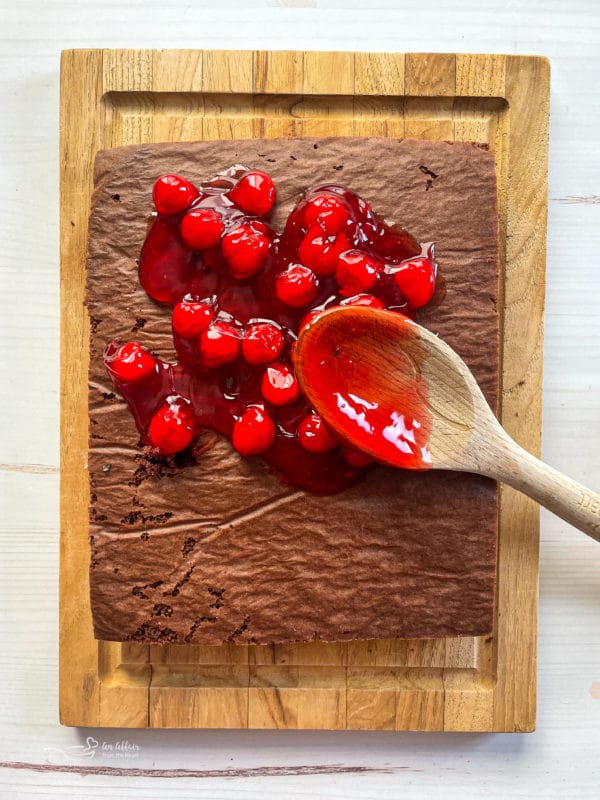 spreading cherry filling over chocolate cake 
