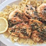 close up of Chicken Piccata and pasta on a white serving platter