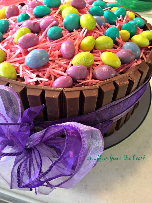 Side view of Easter Basket Kit Kat Cake with a purple ribbon around it.