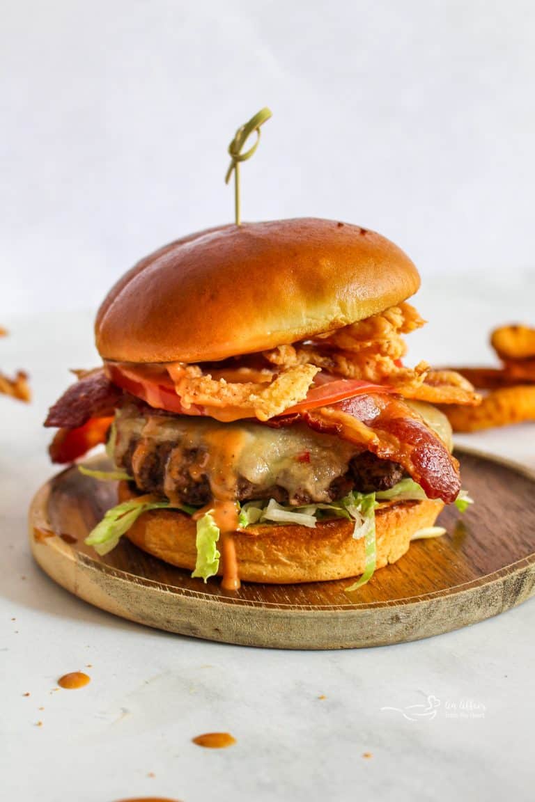 Side view of a Western Burger so you can see all the toppings, melted cheese and sauce dripping down the side.