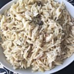 Close up of orzo in a white bowl with text "creamy Mushroom Orzo"
