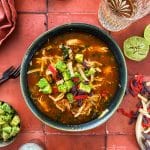 Close up of slow cooker Enchilada soup topped with avocado and tortilla strips.