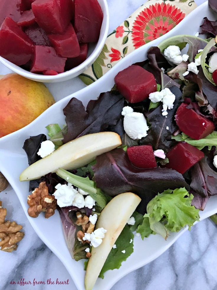 Overhead of Pickled Beet Salad with Pears, Walnuts & Goat Cheese on a white platter