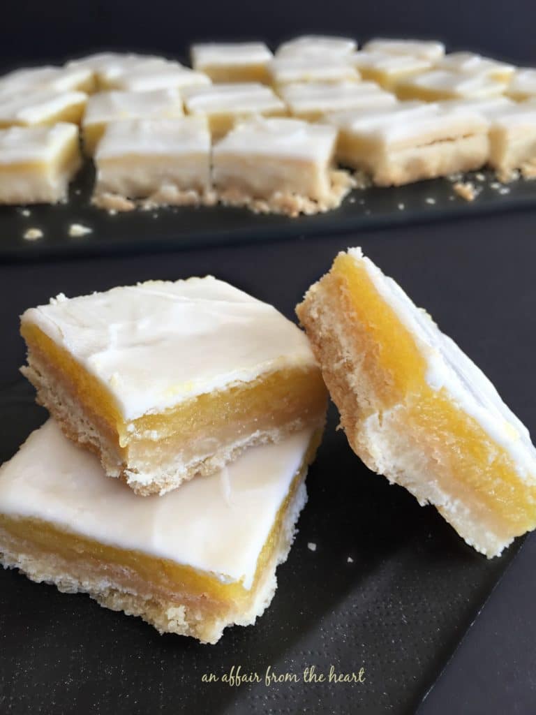 Glazed Lemon Bars stacked on a black napkin