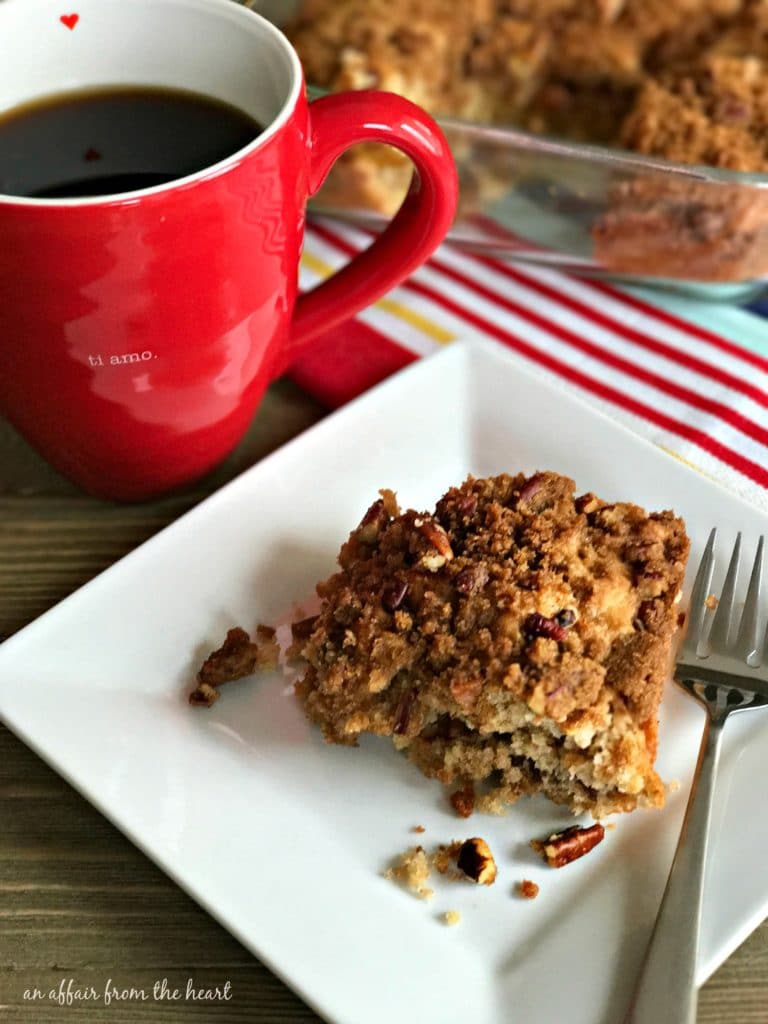 Cinnamon Crunch Coffee Cake on a white plate with a cup of coffee on a table