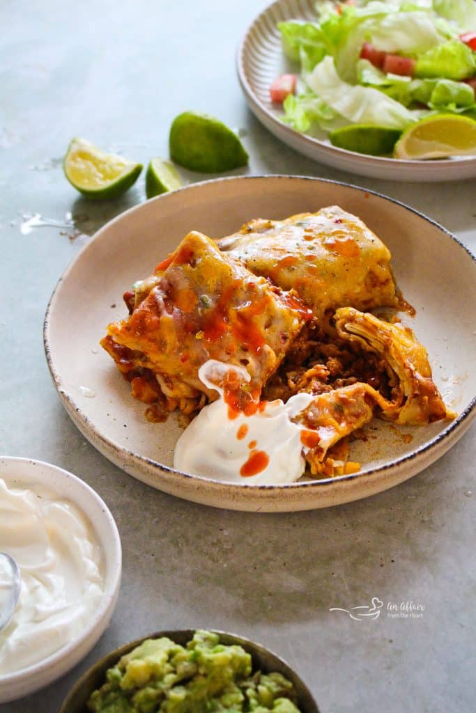 Slow Cooker Smothered Burritos and sour cream on a plate.