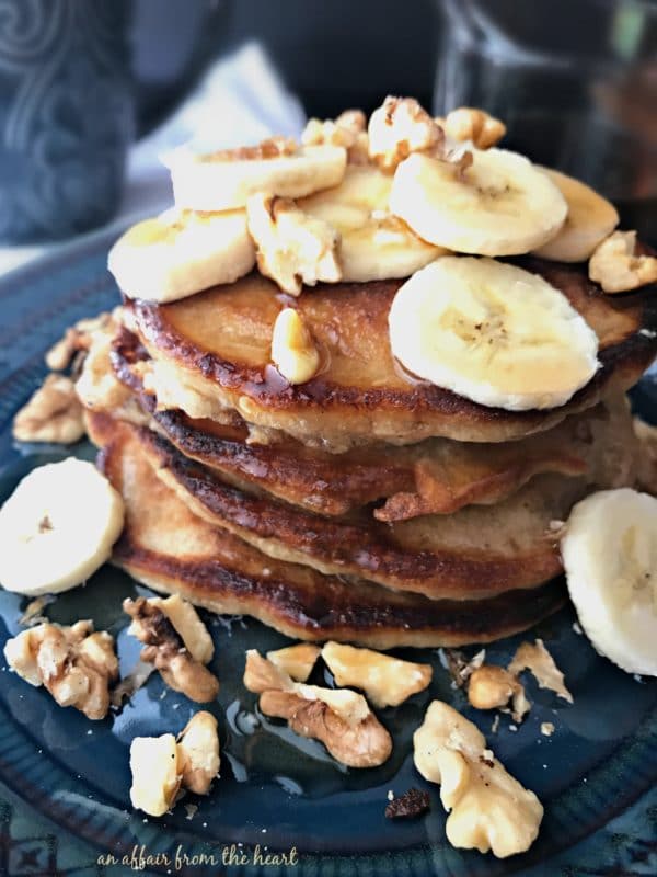 Banana Bread Pancakes topped with bananas and walnuts on a blue plate