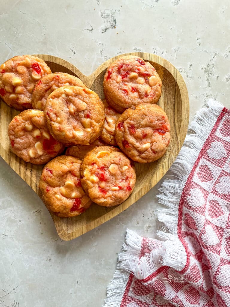 Close up of White chocolate cherry cookies a heart shaped serving dish.