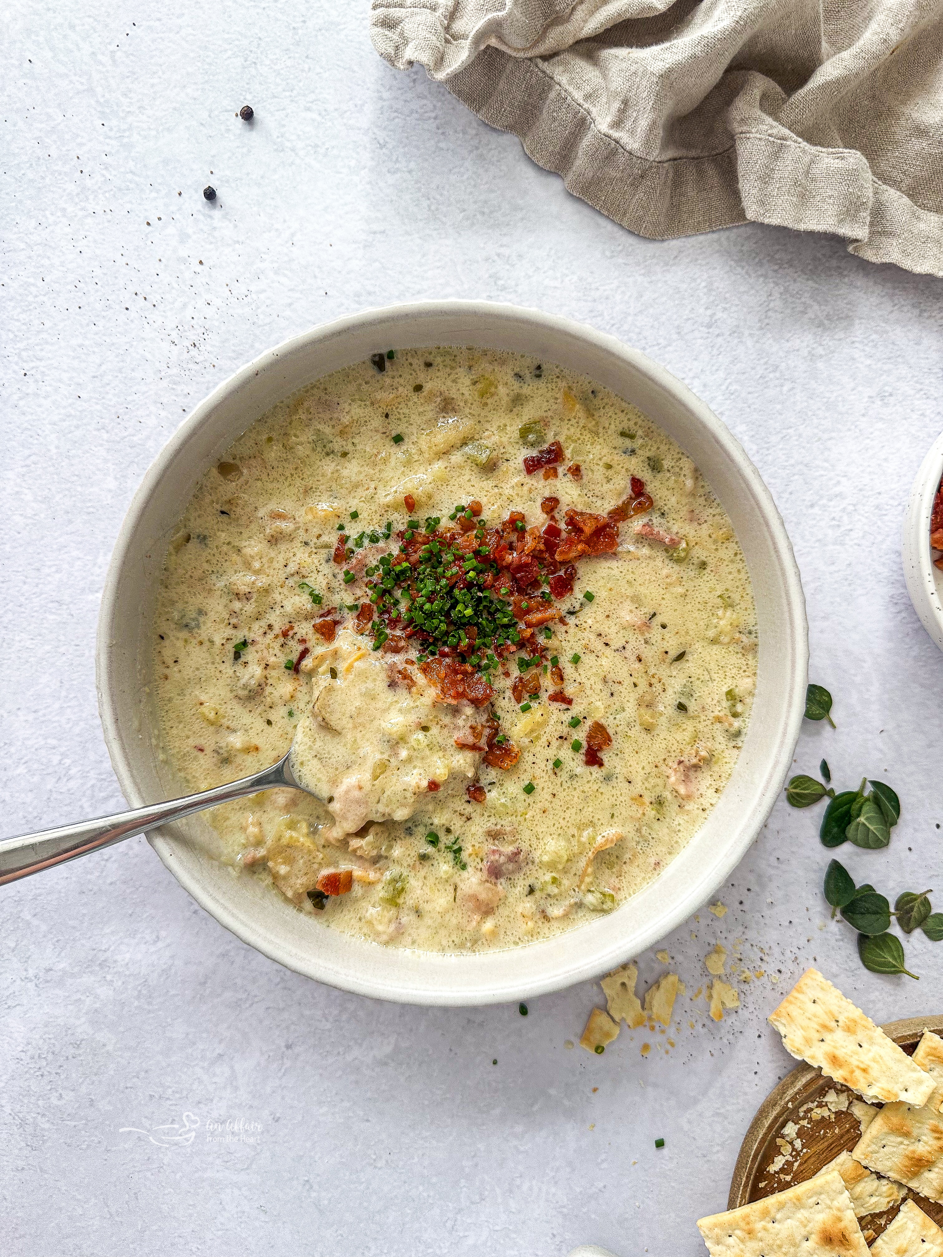 Instant Pot New England Clam Chowder in a white bowl with a spoon in the bowl.