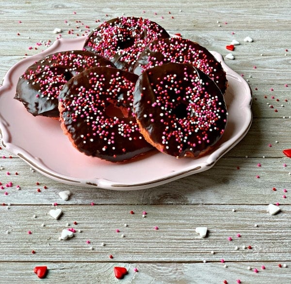 Side view of Baked Chocolate Covered Strawberry Donuts on a pink plate