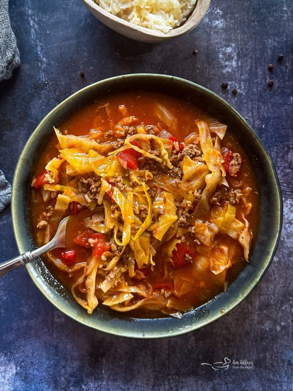 Close up of cabbage roll soup in a blue bowl.