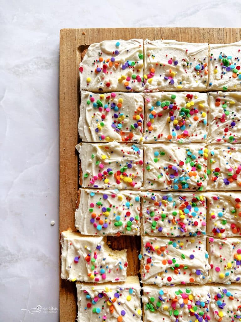 Sliced Frosted sugar cookie bars on a wood board.