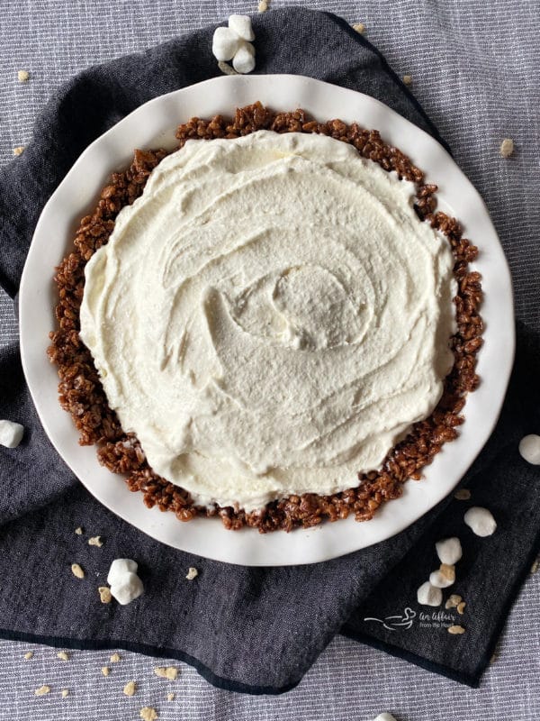 Preparing Chocolate Marshmallow Pie Crust with vanilla ice cream in a white pie plate
