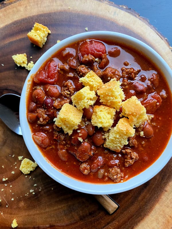 Overhead of 3 bean chili with cornbread in a white bowl