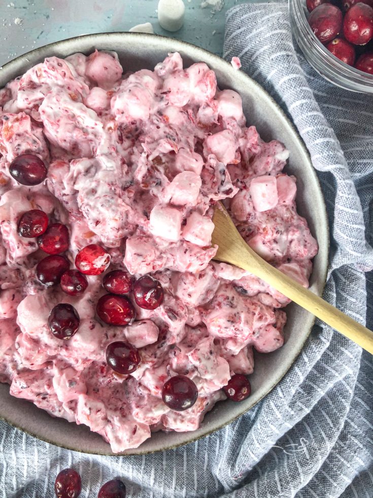Close up of Cranberry Fluff Salad in bowl with light bluish background