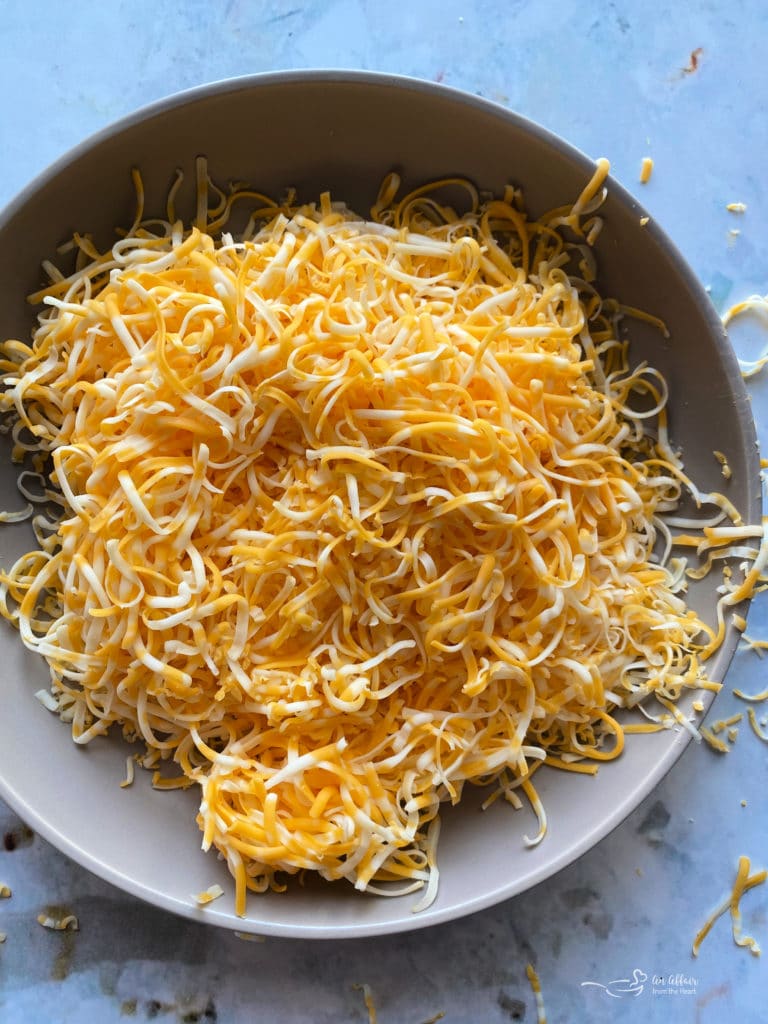 Overhead of shredded cheese in a grey bowl