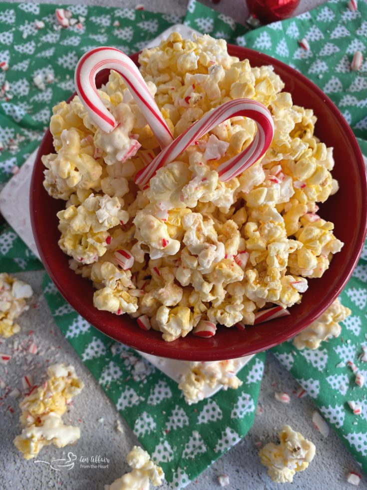 Close up of Peppermint Candy coated popcorn and 2 candy canes in a red bowl