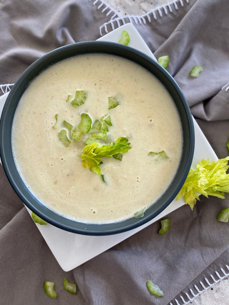 Close up of Cream of celery soup in a blue bowl with gray background