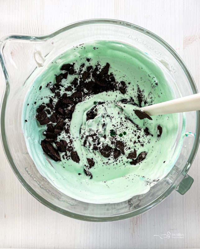 Grasshopper Pie Ice Cream ingredients in measuring bowl with spoon and chopped Oreos