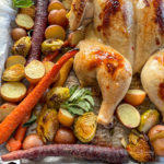 Top view of roasted spatchcock chicken on baking sheet with vegetables