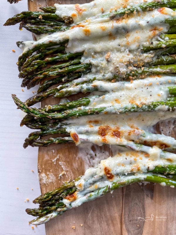 Top view of cheesy asparagus on cutting board