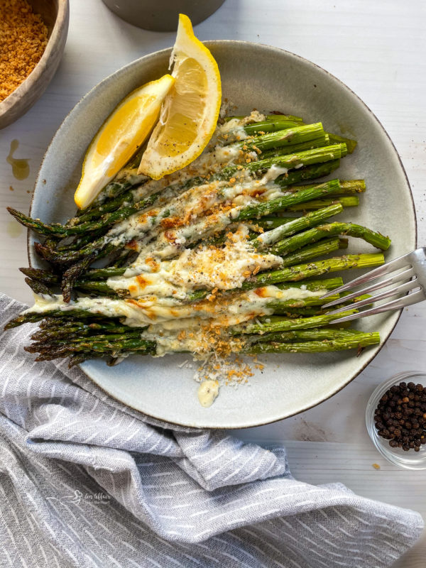 Garlic cheese asparagus in plate with lemon wedges and cheese