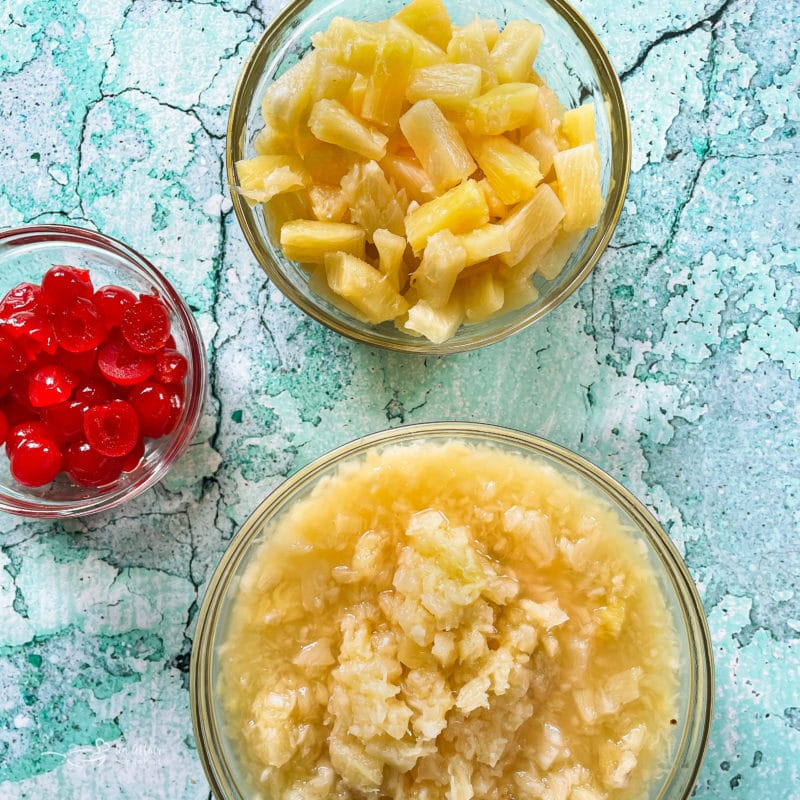 Sliced pineapple, diced pineapple, and bowl of cherries