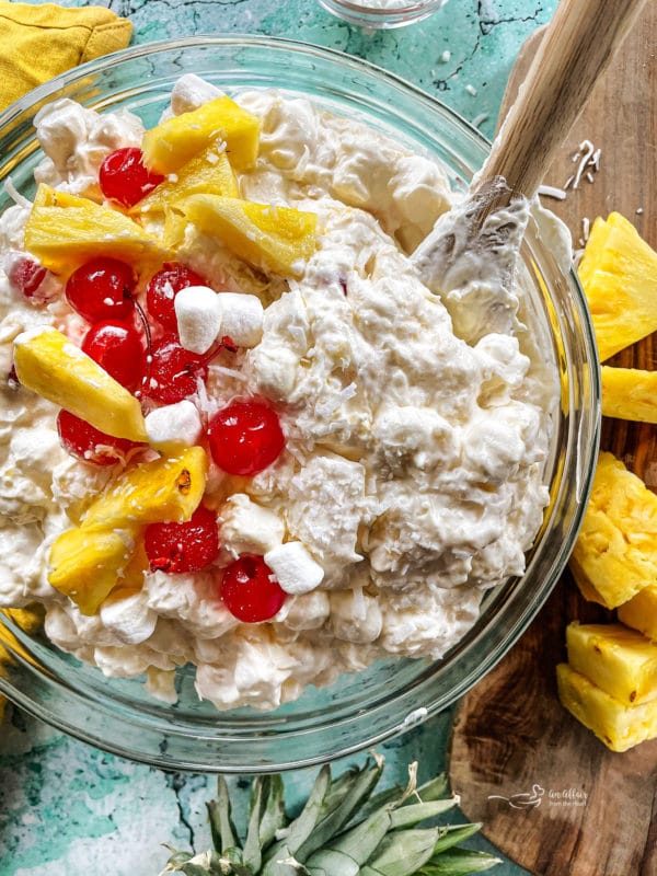Bowl of piña colada fluff with cherries and sliced pineapple