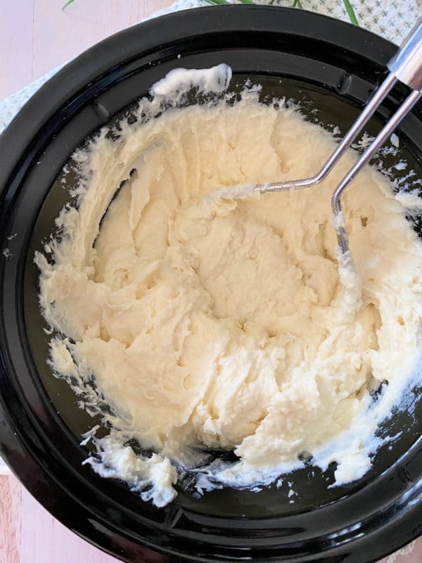 Creamy potatoes in Crockpot with potato masher