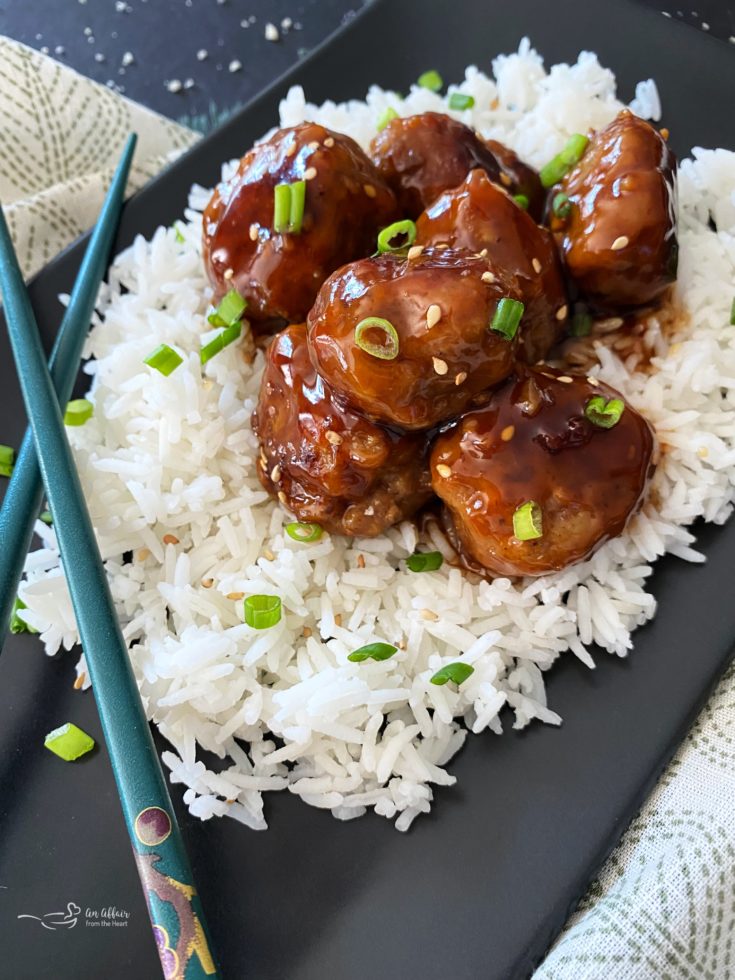 Sticky Asian Meatballs over rice on black plate