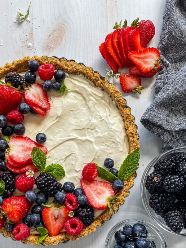 no bake fruit tart on white surface with linen and berries