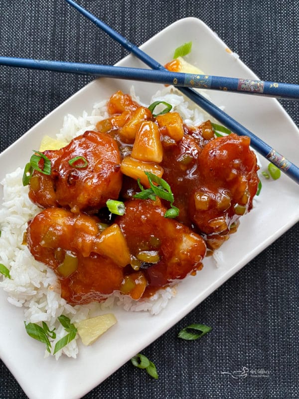 one plate of sweet & sour chicken over rice with chopsticks