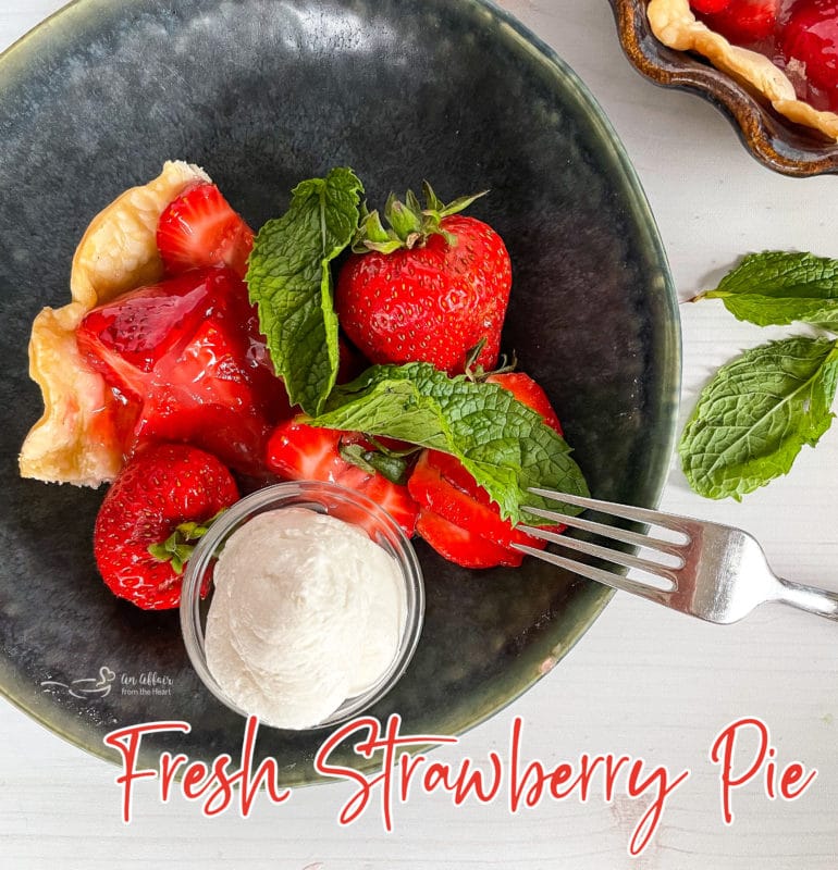 top view of fresh strawberry pie in grey bowl with whipped cream
