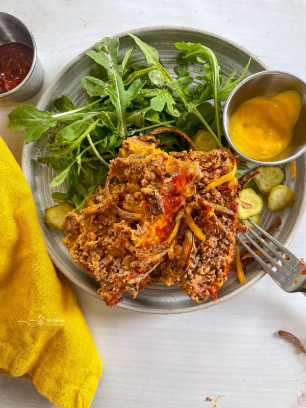 bacon cheeseburger meatloaf on plate with salad and mustard