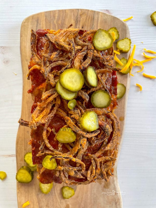 bacon cheeseburger meatloaf topped with fresh pickles and fried onions