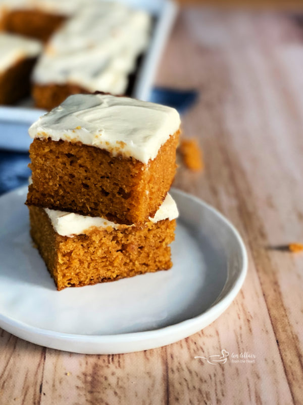 two carrot cake bars with cream cheese frosting on plate