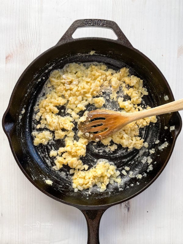 mixing flour and butter with onions and garlic in skillet with spoon