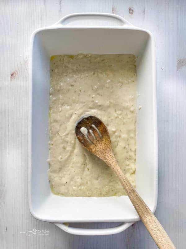 spreading sauce in bottom layer of baking dish with spoon 