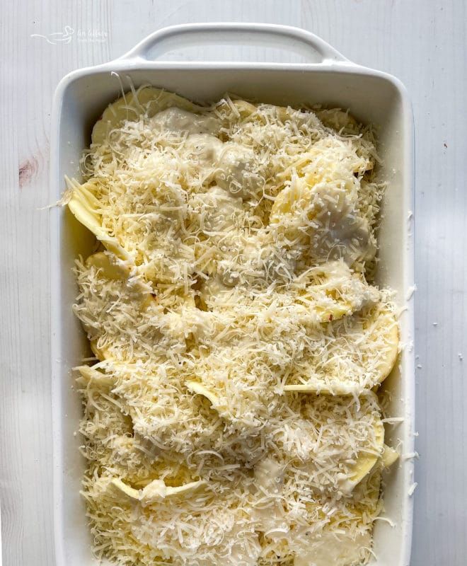 top view of potatoes and cheese being layered in baking dish