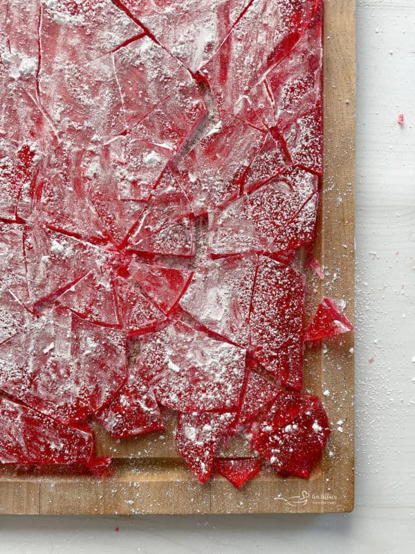 top view of cinnamon candy on cutting board with broken pieces and powdered sugar