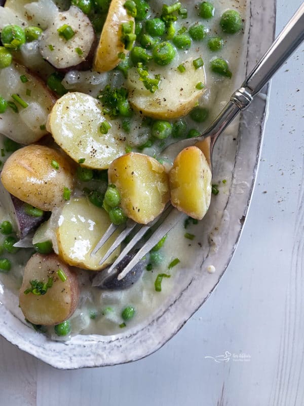 new potatoes and peas with fork in dish