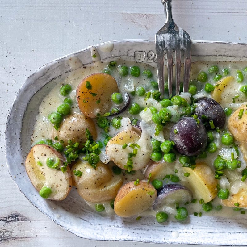 fork in dish with new potatoes and peas